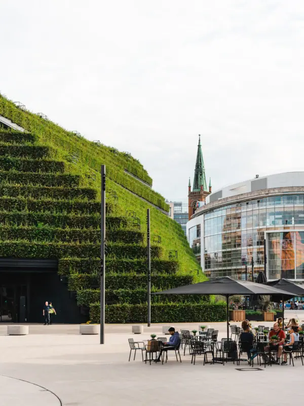 Düsseldorf Ein Gebäude mit einer begrünten Wand in Düsseldorf und Menschen, die an Tischen sitzen.
