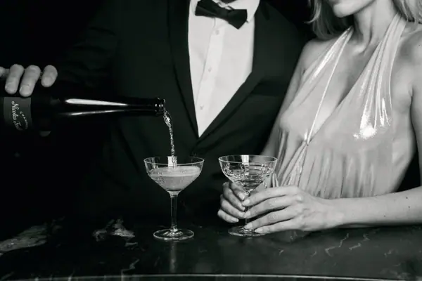 Hotelbar Ein Mann im Anzug und eine Frau im Kleid sitzen an einer Bar mit Weingläsern.