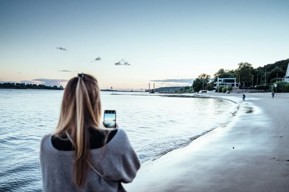 Elbstrand Eine Frau fotografiert den Elbstrand in Hamburg.