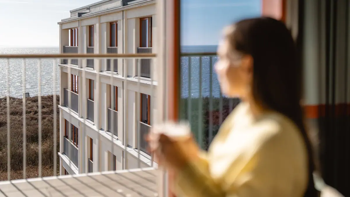 A-ROSA Sylt Ausblick Eine Frau sitzt am Fenster im A-ROSA Sylt und schaut auf die Nordsee.