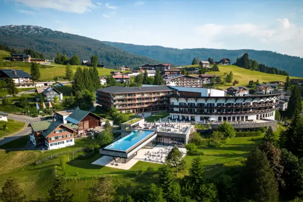 A-ROSA Ifen Hotel Kleinwalsertal Ein Gebäude mit einem Pool mit Bergen im Hintergrund.