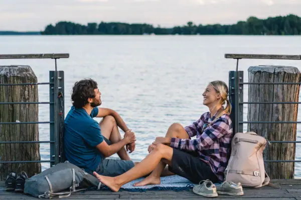 Ein Mann und eine Frau sitzen auf einem Steg am Scharmützelsee.