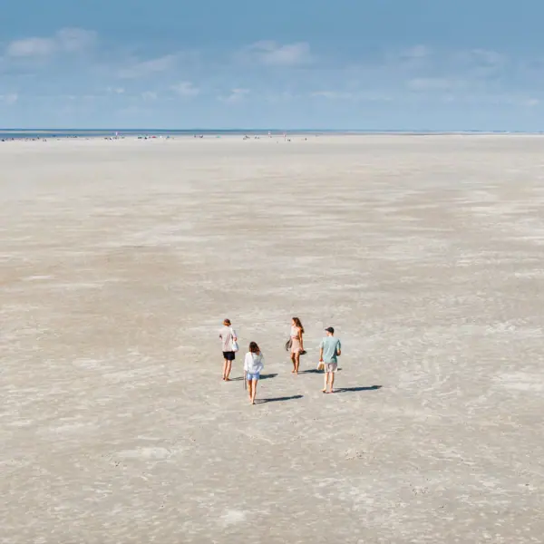 Strand in St. Peter-Ording Eine Gruppe von Menschen läuft am Strand von St. Peter-Ording beim Urlaub am Wattenmeer.