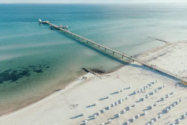 Grömitz Strand Der Strand von Grömitz von oben fotografiert mit türkis blauem Wasser und Strandkörben im Sand.