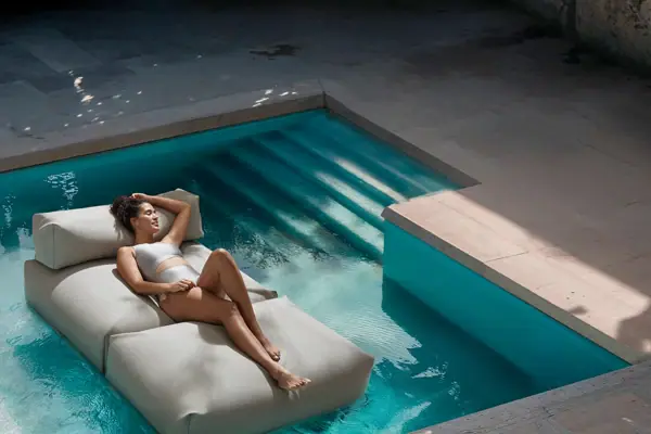 Badesofa Eine Frau liegt auf einer Matratze in einem Pool.