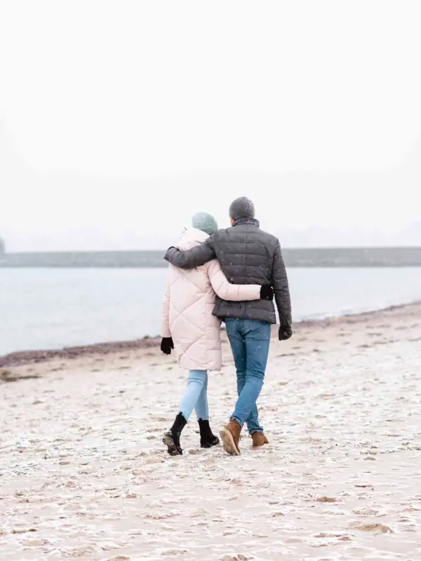 Spaziergang am Strand von Travemünde Ein Mann und eine Frau spazieren am Strand.
