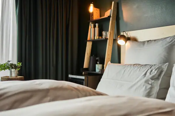 Hotelzimmer Urban Nature SPO Ein Hotelzimmer im Urban Nature Hotel St. Peter-Ording mit einem Bett und einem Regal mit Lichtern.