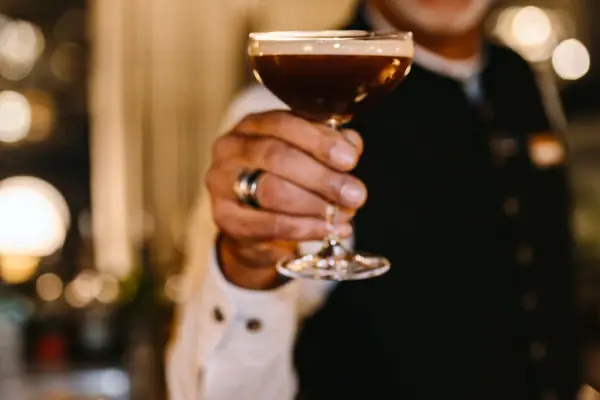 Barkeeper Espresso Martini Ein Barkeeper hält ein Martini-Glas mit einem Espresso Martini.