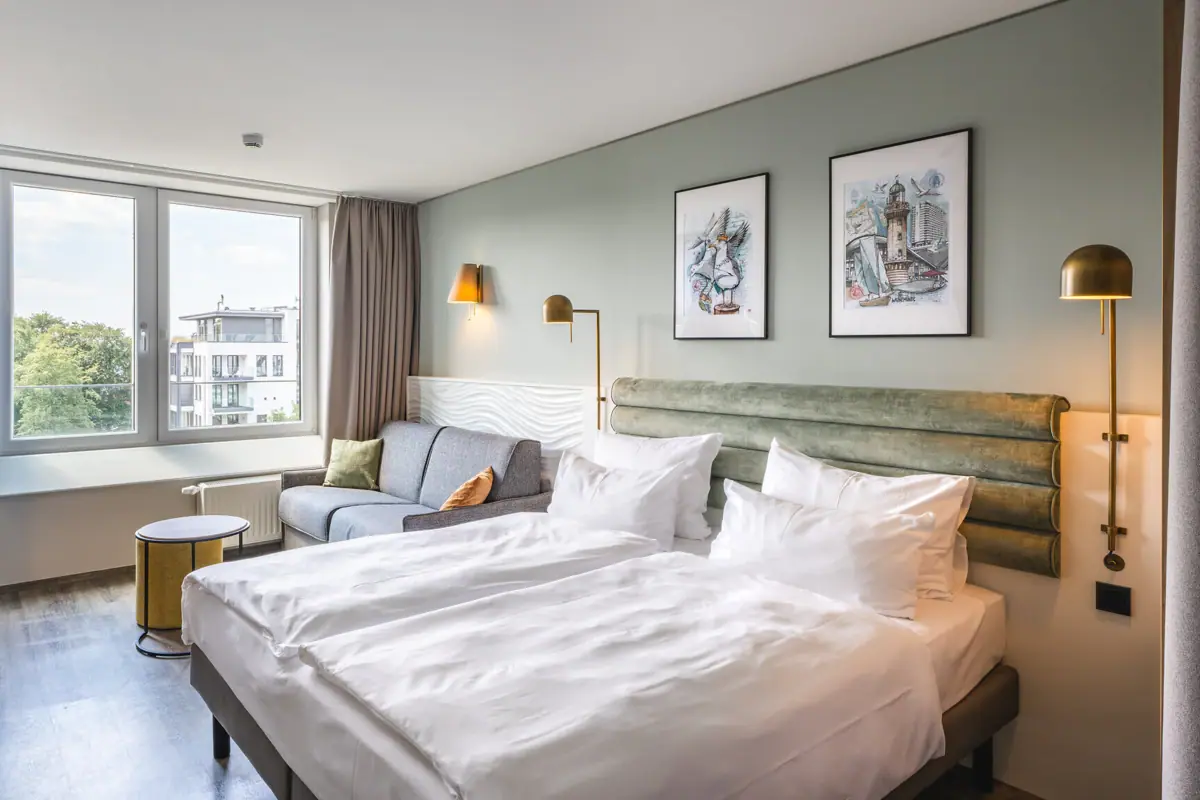 Zimmer im aja Warnemünde Ein Zimmer mit zwei Betten und einem Sofa.