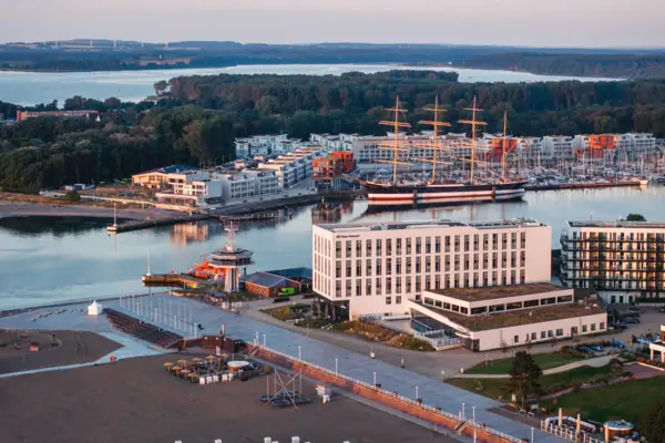 aja Travemünde Das aja Hotel in Travemünde direkt an der Promenade mit der Trave-Mündung, dem Priwall und dem Segelschiff Passat im Hintergrund.