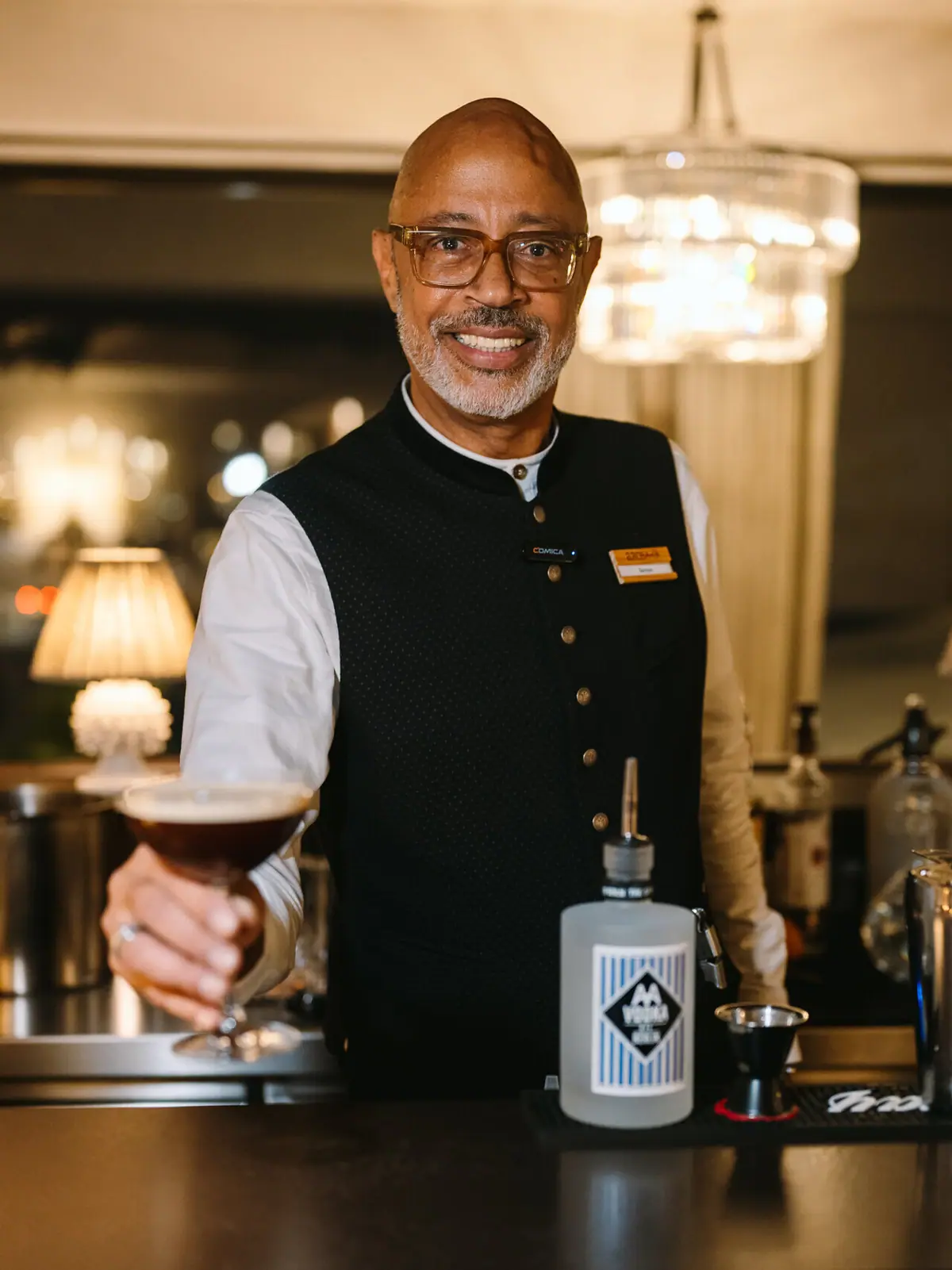 Barkeeper Thurnher’s Alpenhof Ein Barkeeper hält einen Espresso Martini und lächelt.