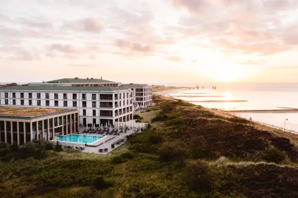 A-ROSA Sylt Ein Gebäude mit einem Pool am Wasser.