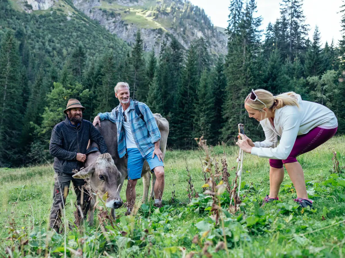 Wolfi Eine Gruppe von Menschen steht auf einem Feld mit Kühen im Bärgunttal.