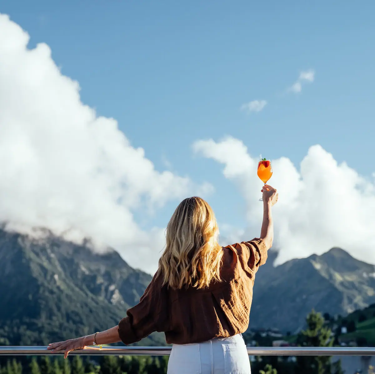 Eine Frau hält einen Cocktail in den Bergen.