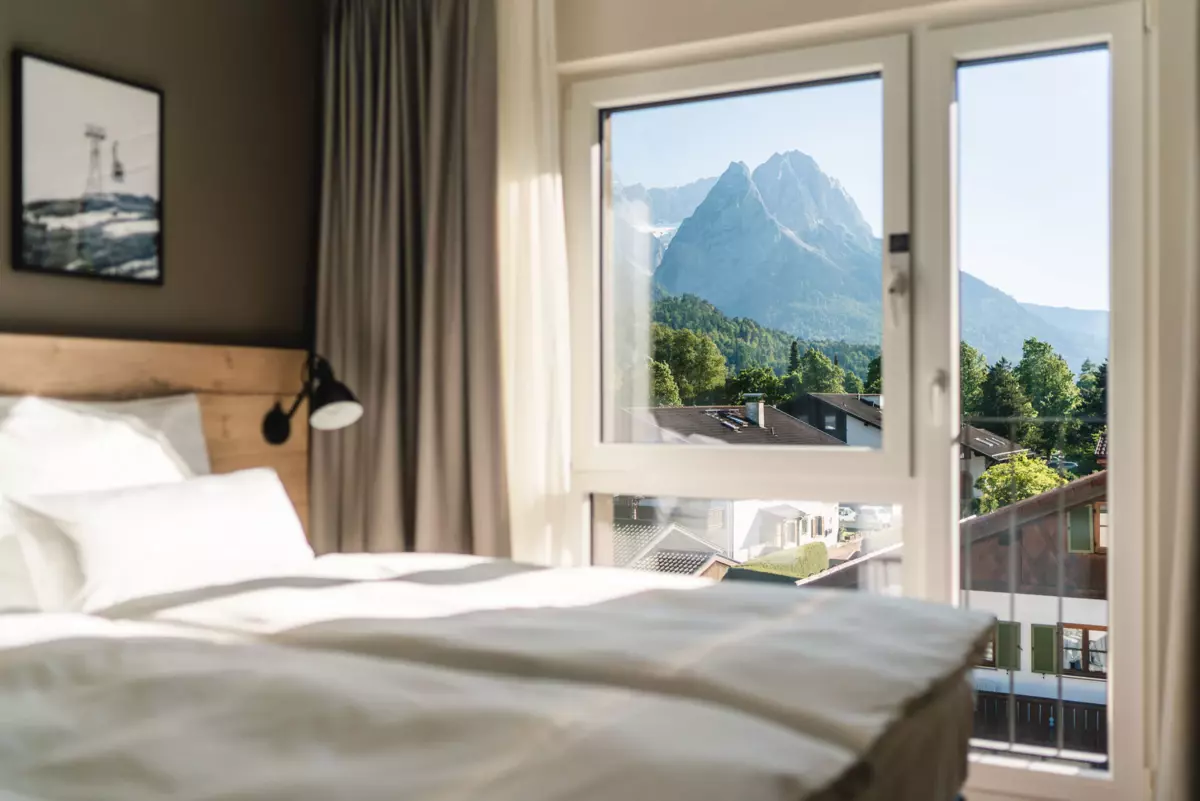 Zimmer im aja Garmisch-Partenkirchen Ein Schlafzimmer im aja Garmisch-Partenkirchen mit einem Fenster und Blick auf Berge.