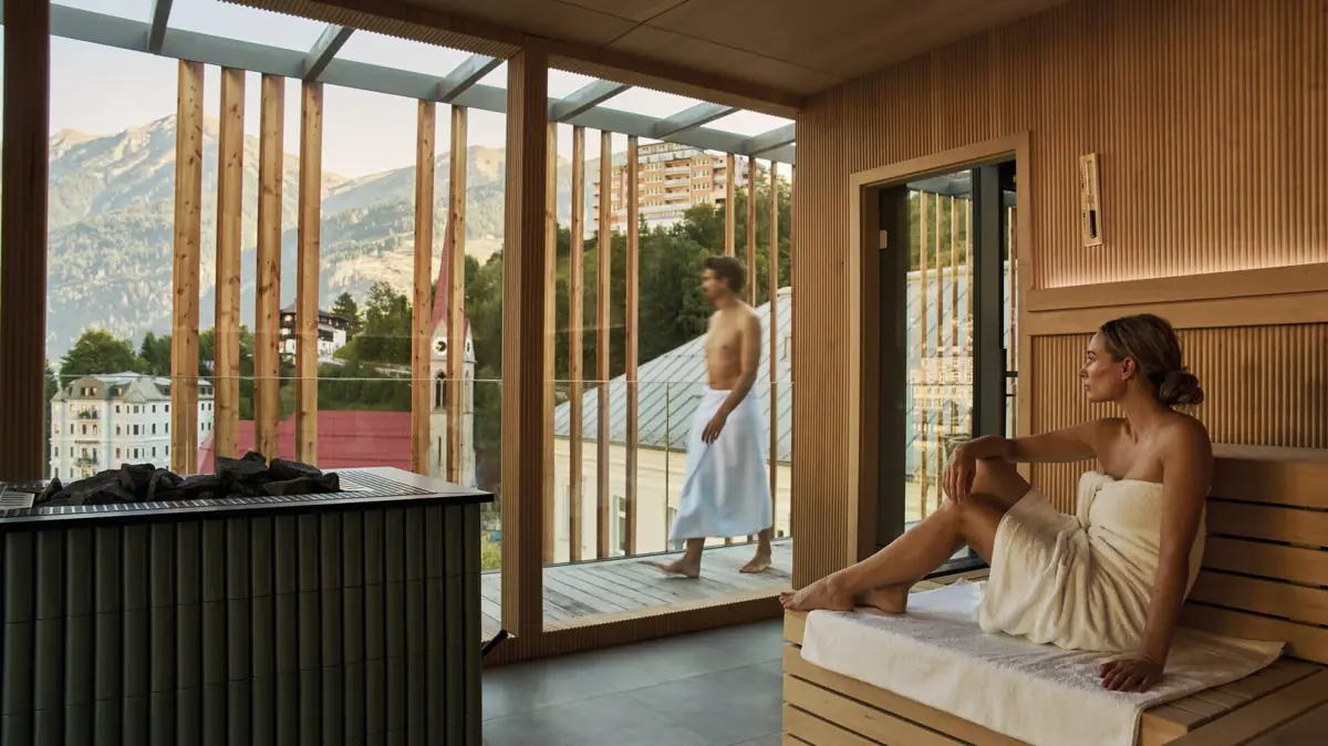Sauna im SPA-ROSA Bad Gastein Eine Frau sitzt in einer Sauna und schaut nach draußen.