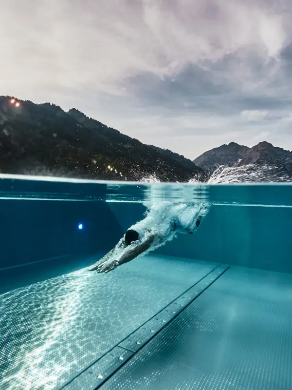 Entspannung Eine Person schwimmt in einem Pool mit Bergen im Hintergrund.