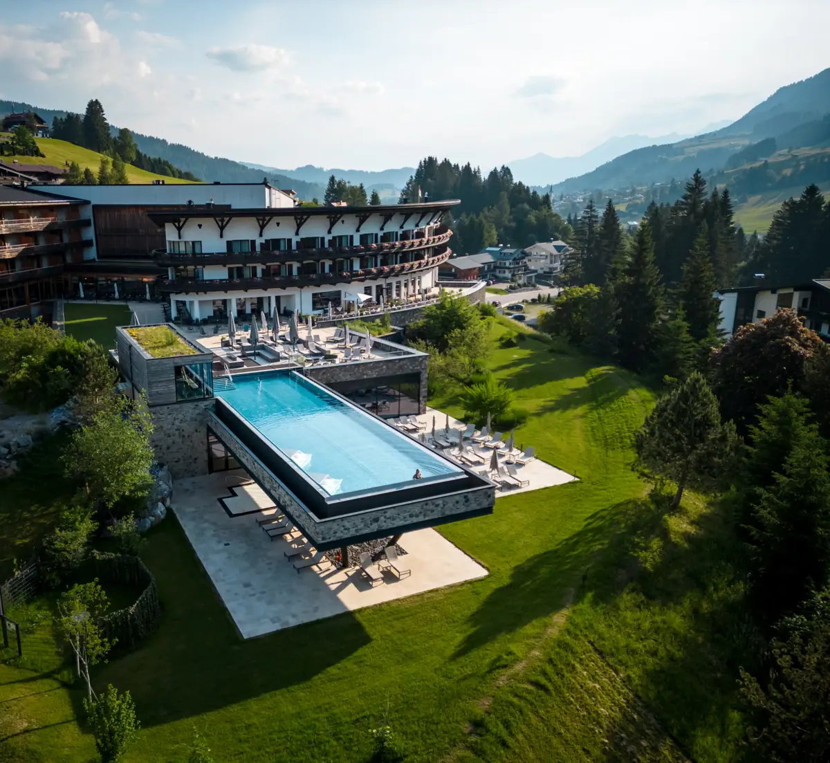 A-ROSA Ifen Hotel Kleinwalsertal Ein Swimmingpool im A-ROSA Ifen Hotel Kleinwalsertal, umgeben von Bäumen und klarem Himmel.