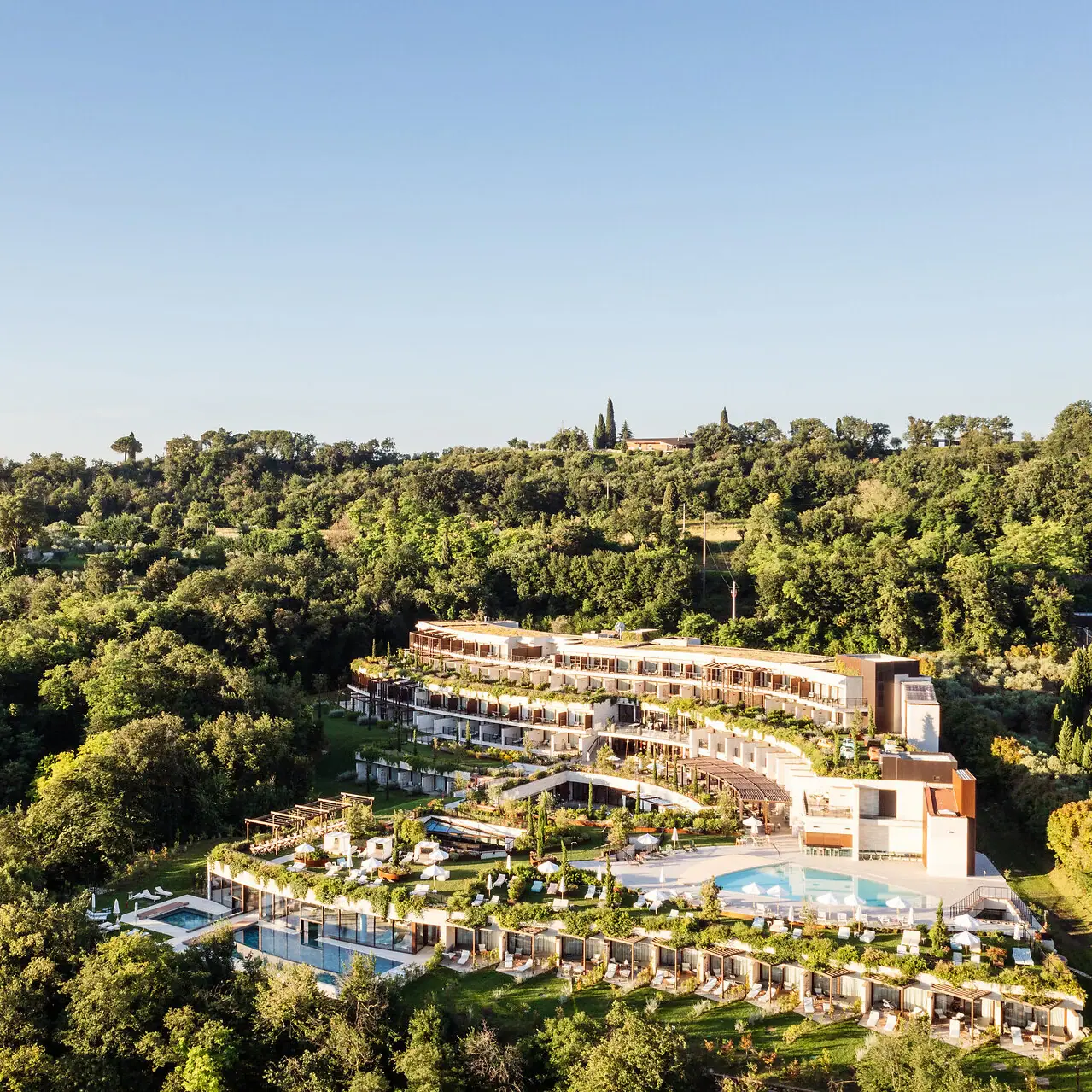 A-ROSA Gardasee Ein Gebäude mit einem Pool, umgeben von Bäumen.
