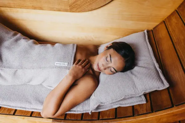 Saunasofa Eine Frau liegt in einer hölzernen Sauna.