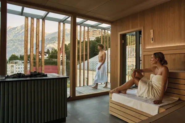 Sauna im SPA-ROSA Bad Gastein Eine Frau sitzt in einer Sauna und schaut nach draußen.