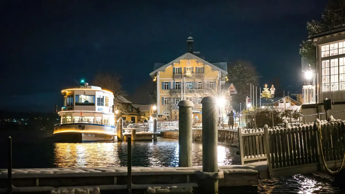 Pendelschiff Tegernsee Ein Boot an einem Steg im Wasser bei Nacht.
