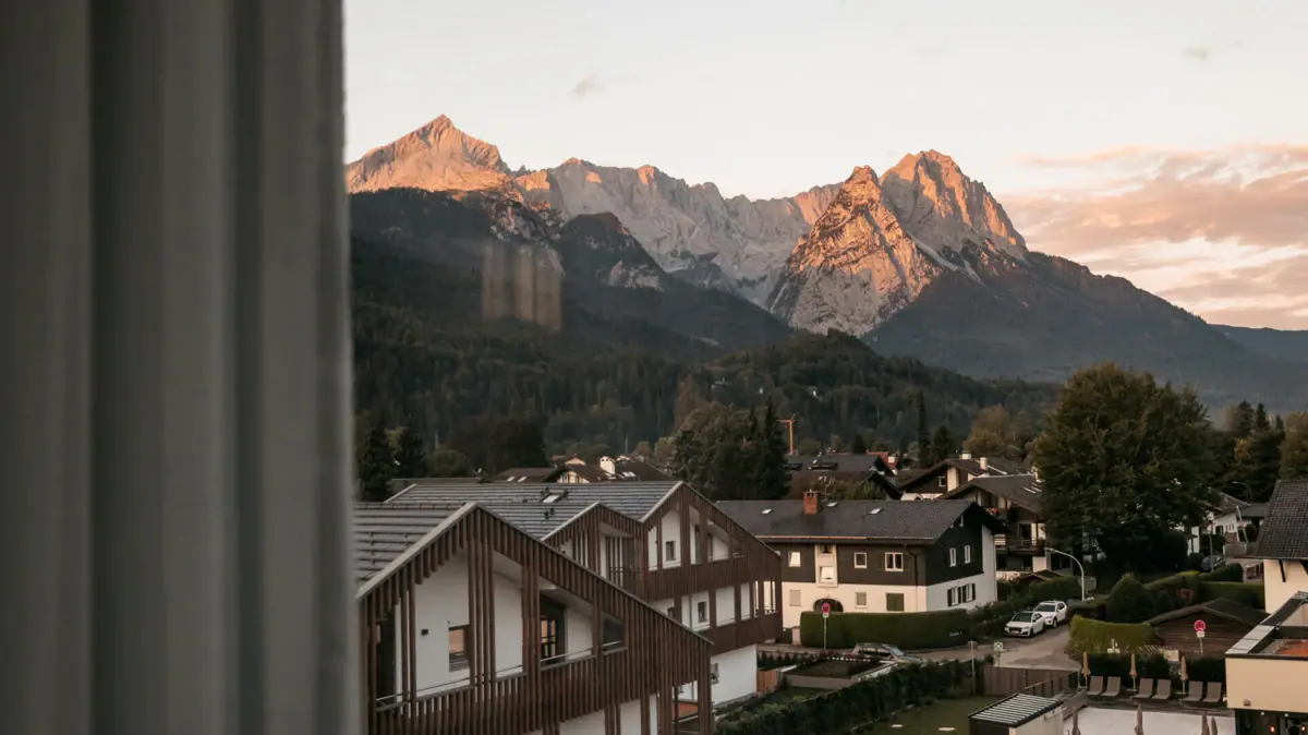 Blick auf die Zugspitze aus dem aja Garmisch-Partenkirchen Ausblick aus dem aja Garmisch-Partenkirchen auf ein Gebirge durch ein Fenster.