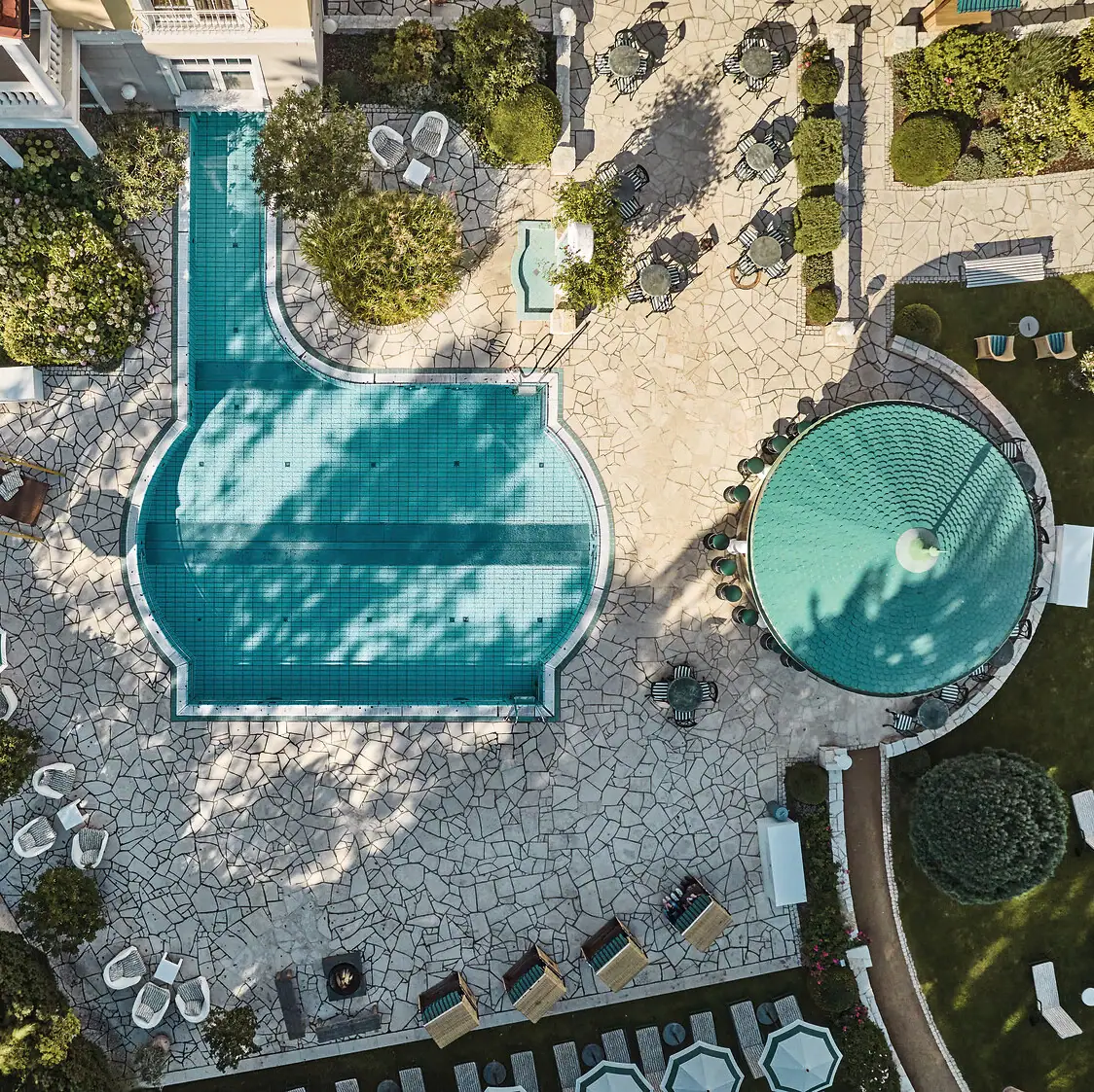 Wellness im A-ROSA Strandidyll Heringsdorf Pool mit Liegestühlen und Bäumen im Hintergrund.