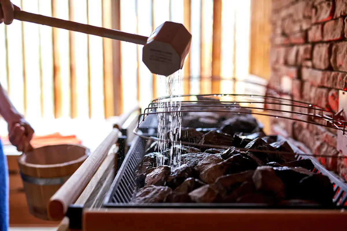 Sauna im SPA-ROSA Ein Holzhammer gießt Wasser auf einen Grill.