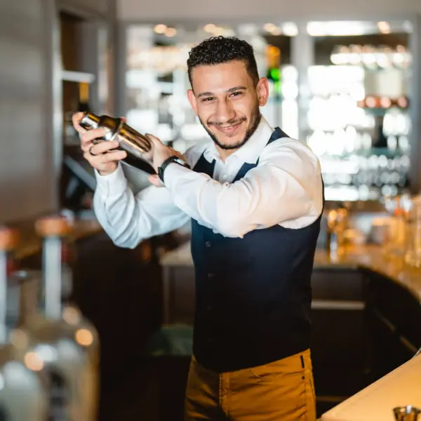 Barkeeper Ein Barkeeper in einer Hotelbar hält einen Shaker.