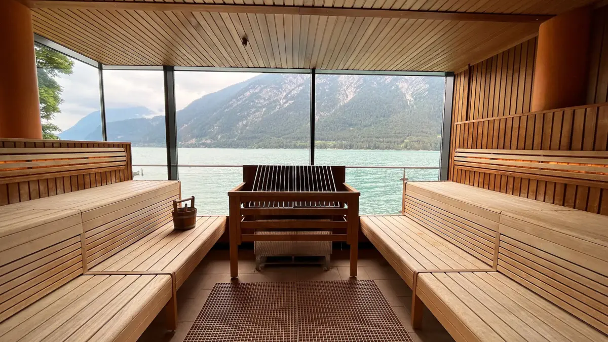 Sauna im aja Achensee Ein Zimmer mit Blick auf Wasser und Berge durch ein großes Fenster.
