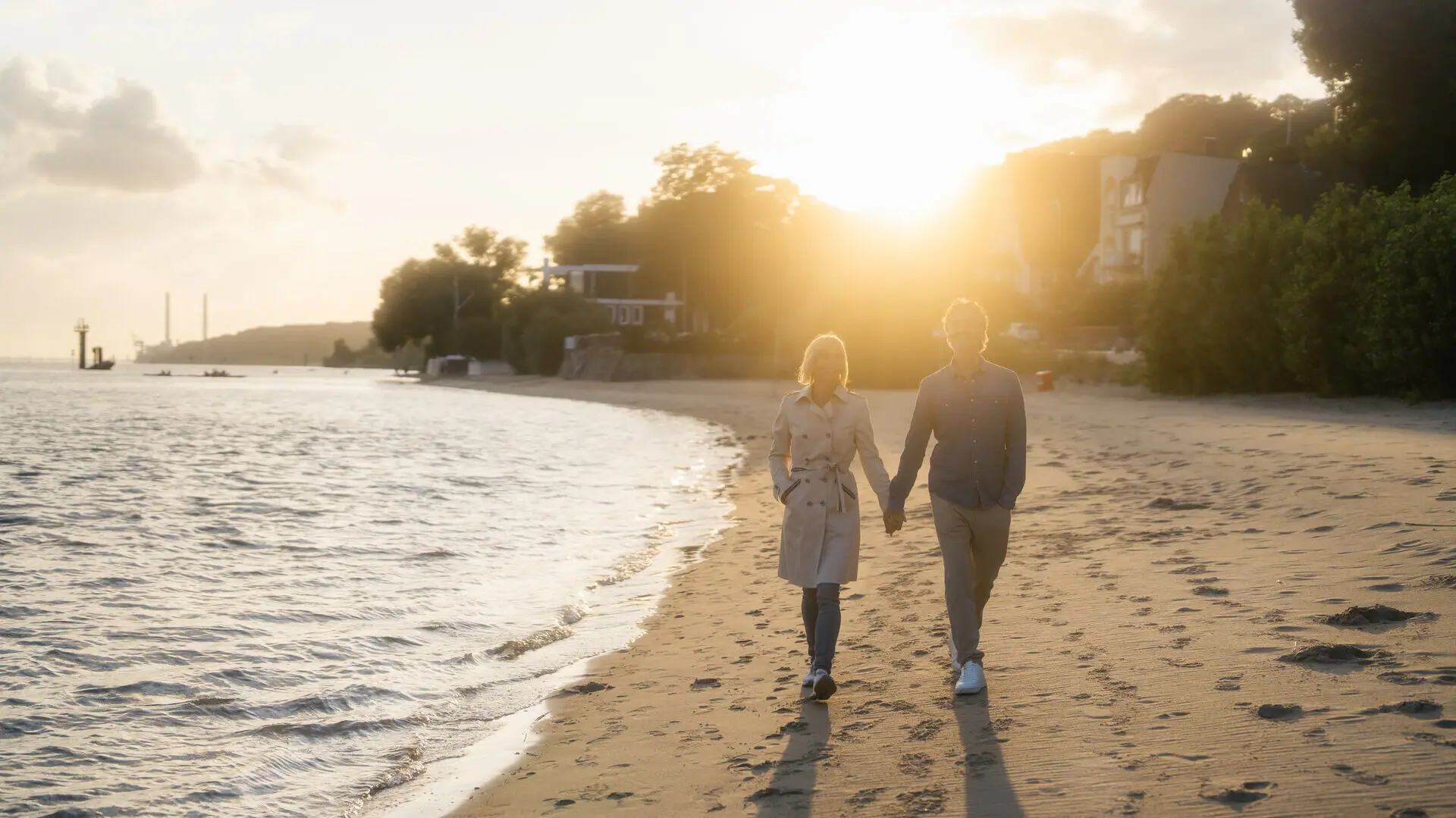 Strand Hamburg Ein Mann und eine Frau halten sich an den Händen am Elbstrand.
