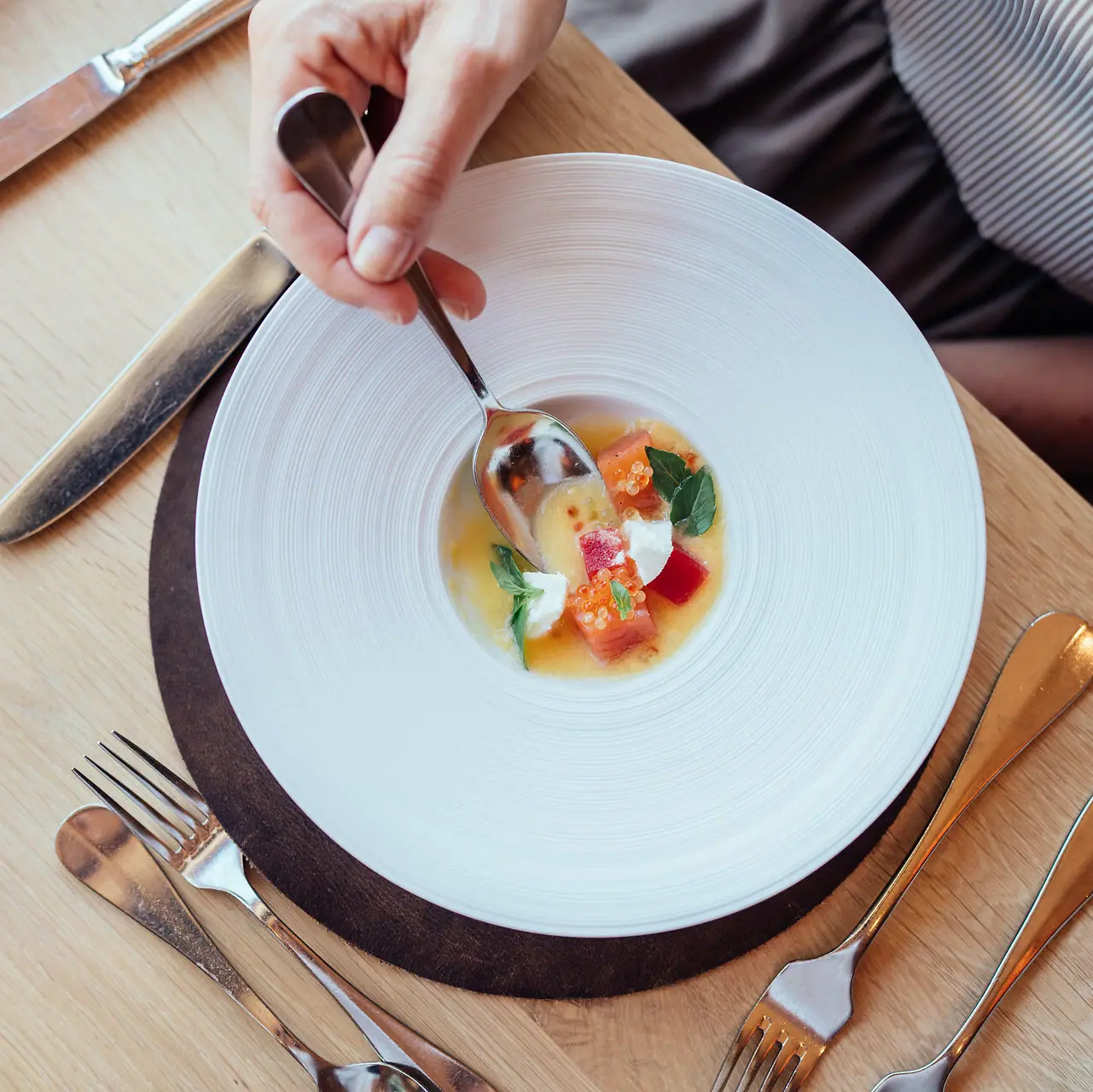 Rezepte Eine Person hält einen Löffel in einer Schüssel Suppe.