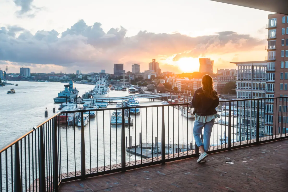 Hamburg Elbphilharmonie Eine Frau steht auf der Elbphilharmonie Plaza und blickt auf die Elbe mit Booten im Hintergrund.