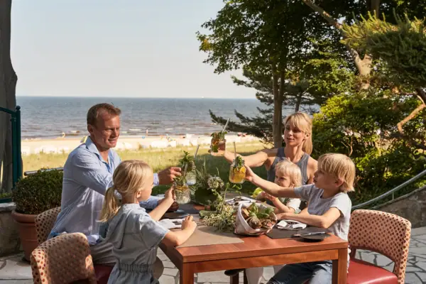 Terrasse im aja Bansin Eine Gruppe von Menschen sitzt an einem Tisch mit Getränken.