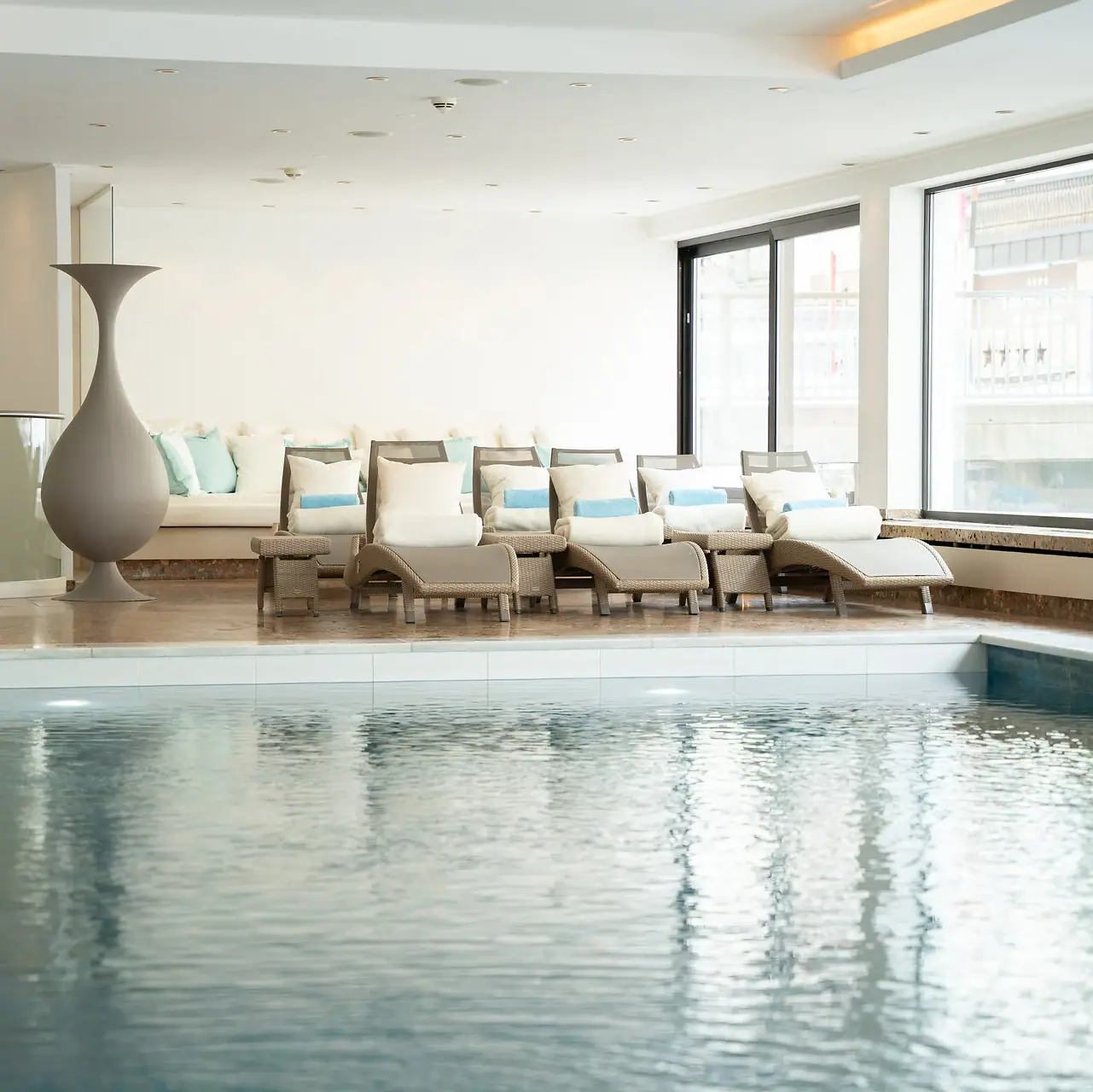 Wellness im A-ROSA Zürs am Arlberg Innenpool mit großer Vase und Stühlen.