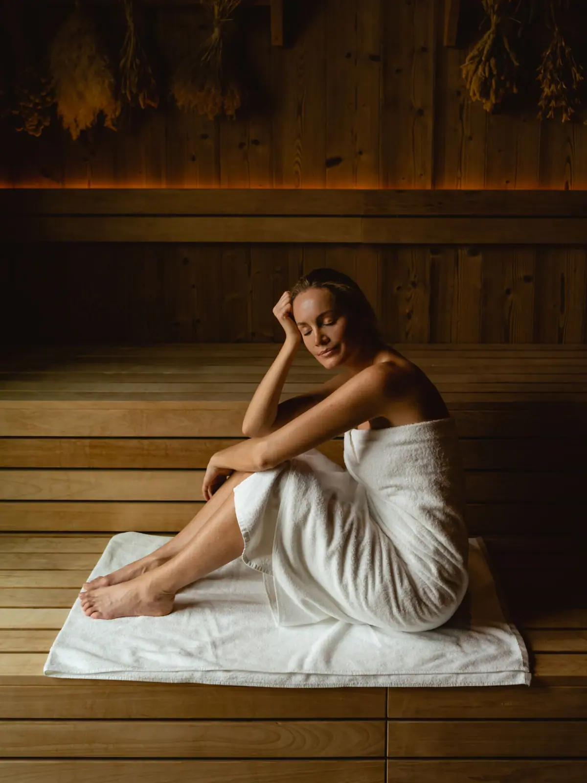 Sauna im SPA-ROSA Sylt Eine Frau sitzt auf einem Handtuch in einer Sauna.