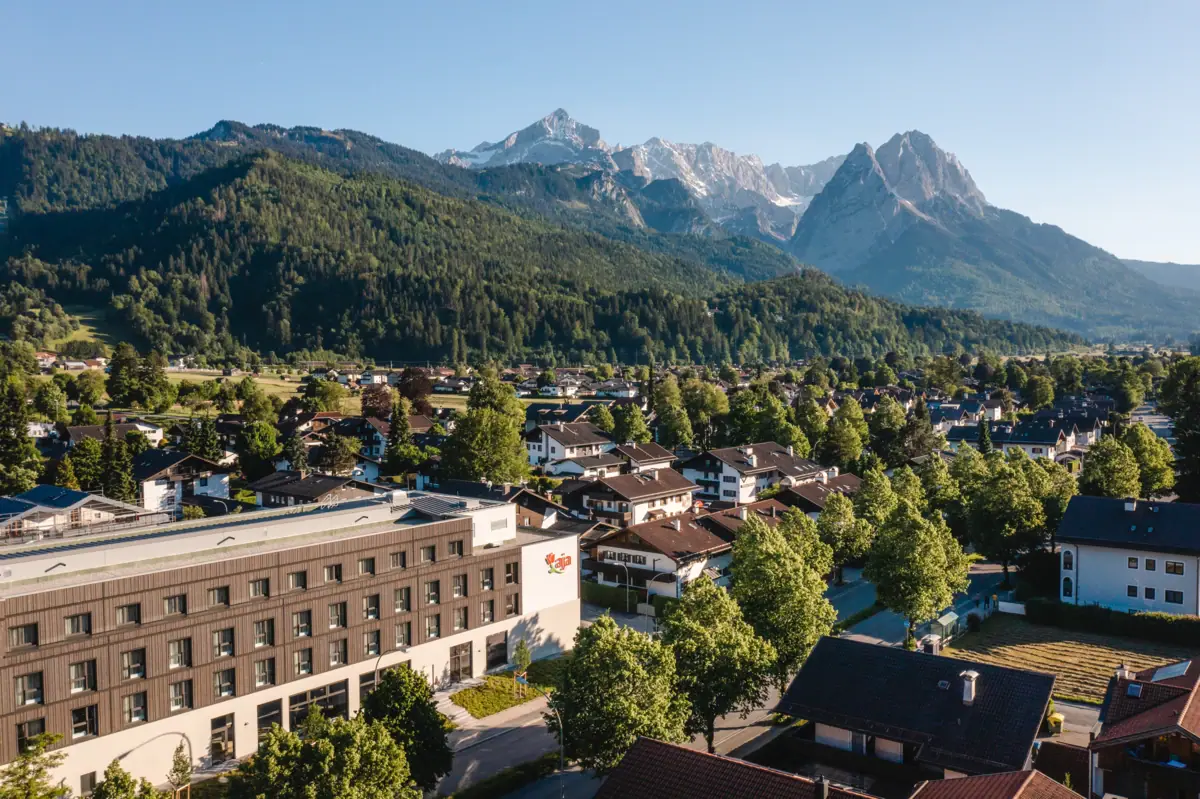 aja Garmisch-Partenkirchen Das aja Garmisch-Partenkirchen mit Bäumen und Bergen im Hintergrund