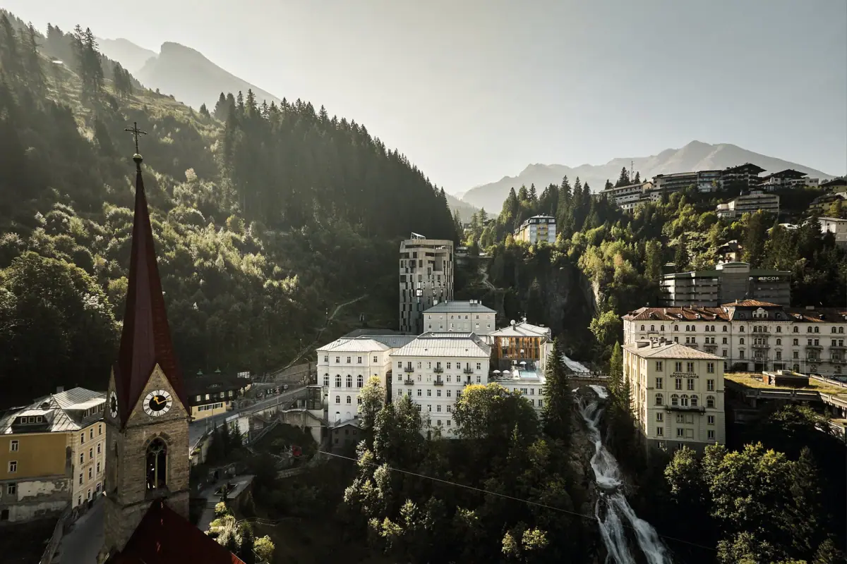 Bad Gastein Eine Luftaufnahme aus Bad Gastein mit einer Kirche und dem Gasteiner Wasserfall mit Bergen im Hintergrund.