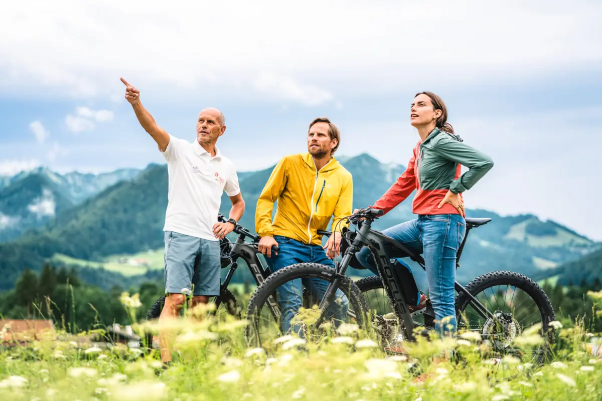 Fahrradtour in Ruhpolding Eine Frau und ein Mann mit Mountainbikes vor Bergkulisse mit einem Tourguide