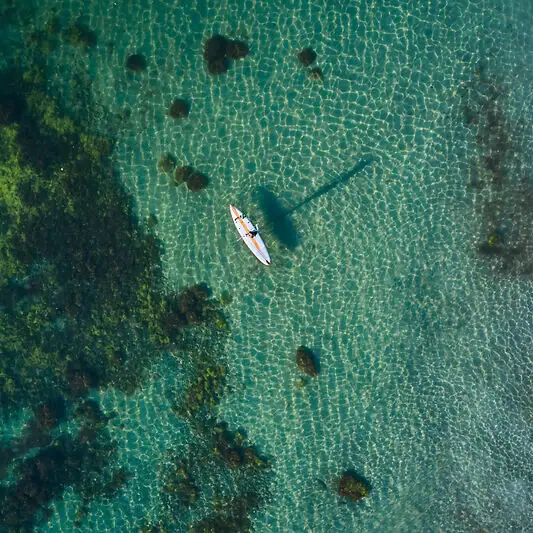 Erlebnisse Eine Person auf einem Surfbrett im Wasser.