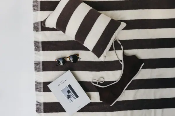 Beachset Schwarz-weiß gestreifte Decke mit einem Kleidungsstück und Sonnenbrille.