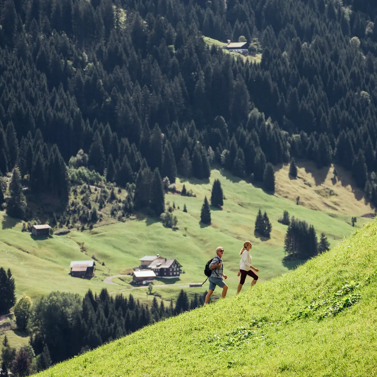 Wandern durchs Bärgunttal Ein Paar geht einen Hügel hinauf, im Hintergrund sind Bäume zu sehen.