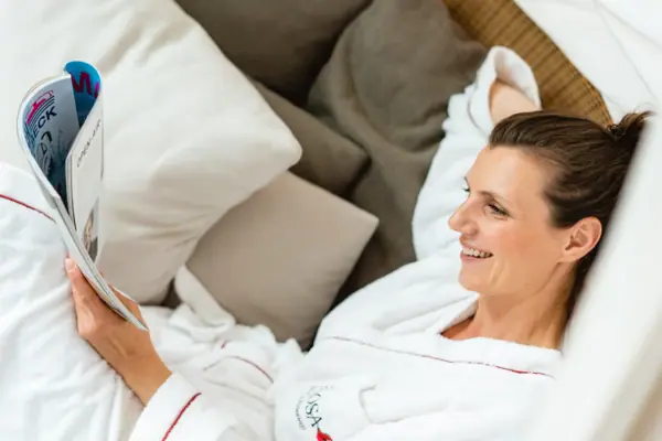 Spa-Bereich im A-ROSA Travemünde Eine Frau im Bademantel liegt auf einer Liege und liest.