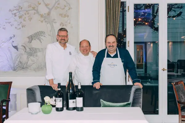 Küchenparty im Louis C. Jacob Eine Gruppe von Männern steht vor einem Tisch mit Weinflaschen.