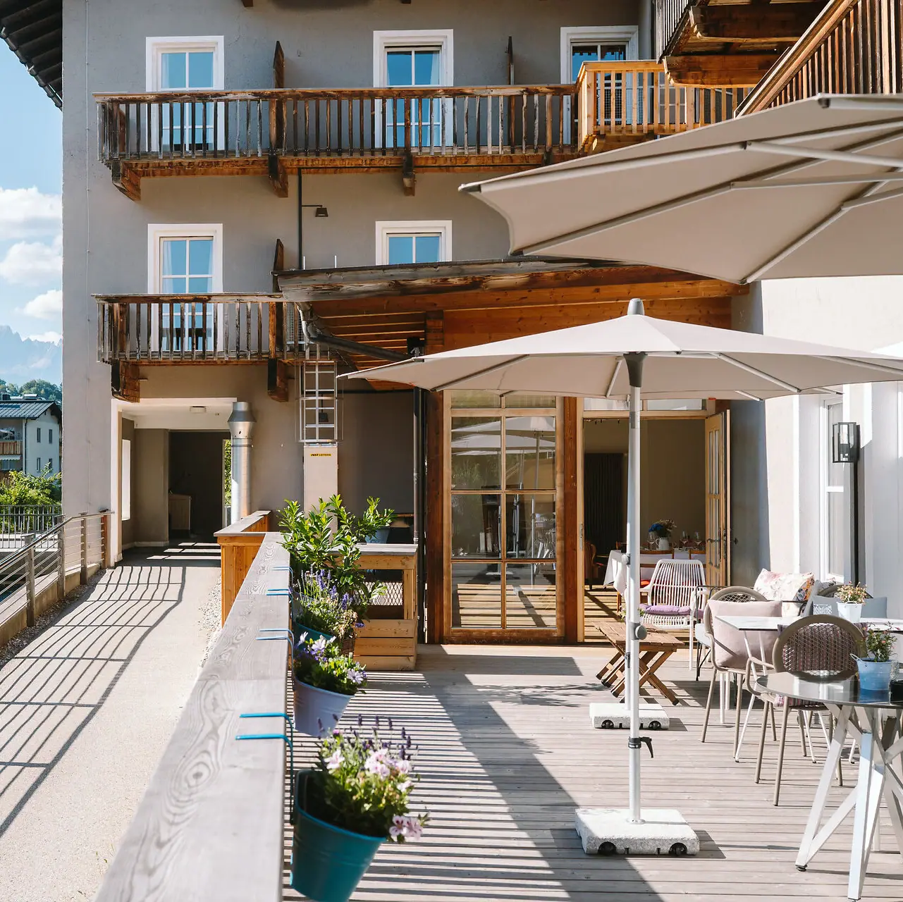 HENRI Kitzbühel Die Terrasse vom HENRI Hotel in Kitzbühel neben einem Fluss und mit Bergblick.