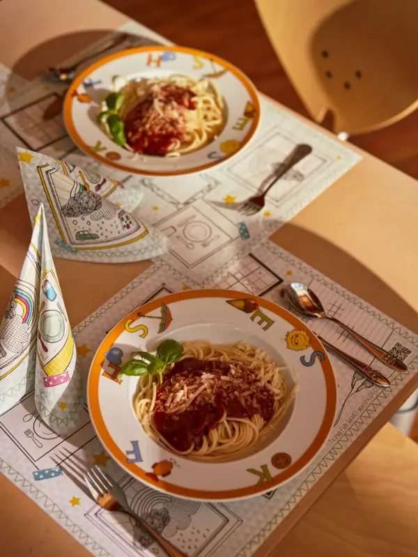 Kindergericht im aja Bansin Teller mit Spaghetti und Soße auf einem Tisch