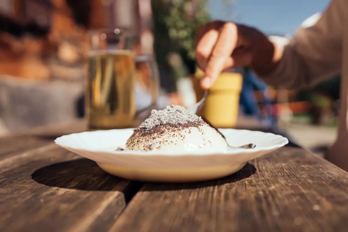 Einkehr in der Bärgunthütte Eine Hand hält einen Löffel über einem Germknödel in der Bärgunthütte.