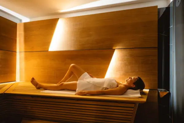 SPA-ROSA Sauna Eine Frau liegt auf einer Bank in einer Sauna.