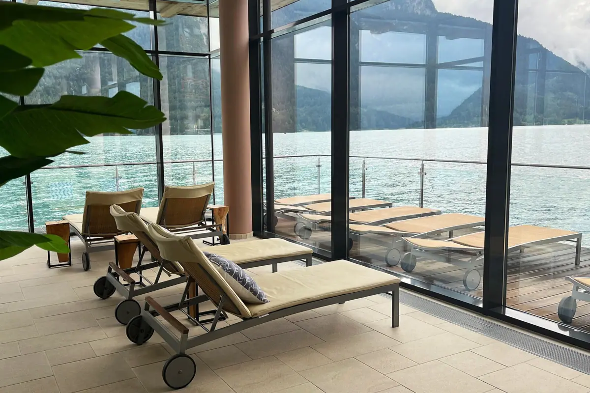 aja Fürstenhaus am Achensee Wellness Der Wellnessbereich im aja Fürstenhaus am Achensee mit Liegen vor großen Fensterscheiben und Blick auf den See.
